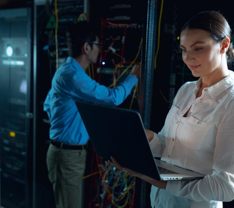 Caucasian female engineer using laptop and asian male engineer inspecting in computer server room. database server management and maintenance concept Caucasian female engineer using laptop and asian male engineer inspecting in computer server room. database server management and maintenance concept